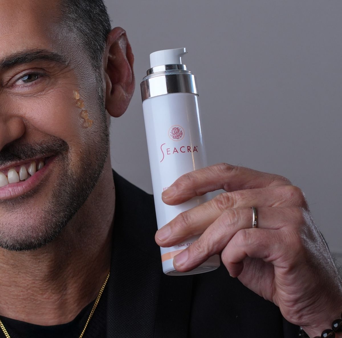 Male model holding Seacra red algae gel with a dab of gel on his cheek