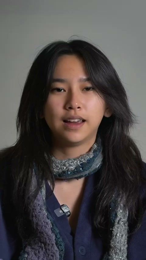 Young woman speaking to camera in a talking head skincare video against a grey wall