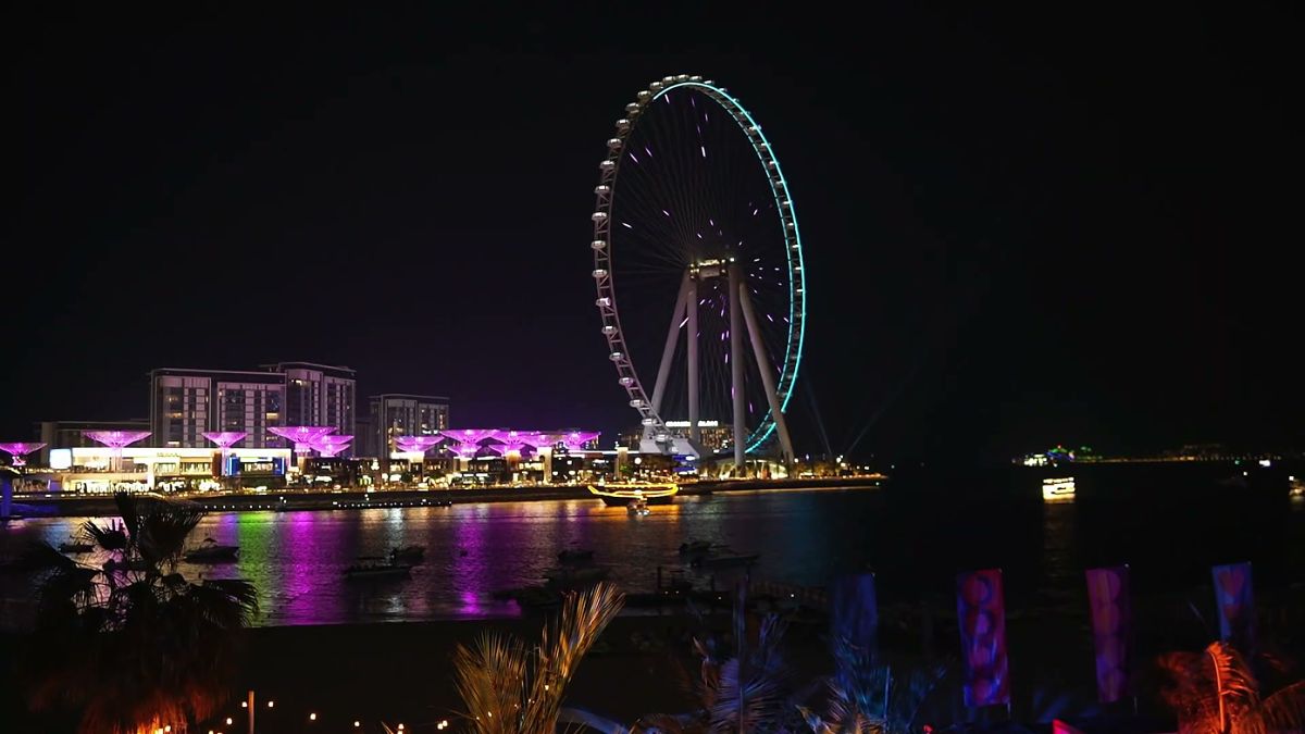 Ain Dubai and Bluewaters lit up at night across the water, an establishing shot
