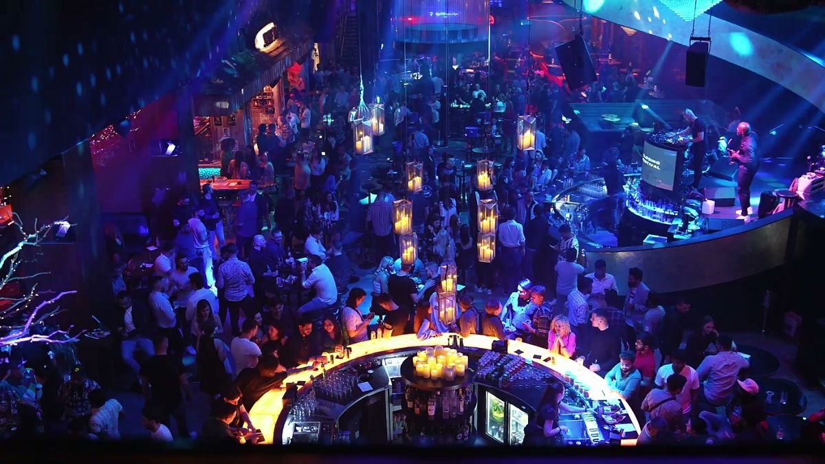 High angle over a packed crowd around a round bar at the Affiliate World x Shinz closing party, Dubai
