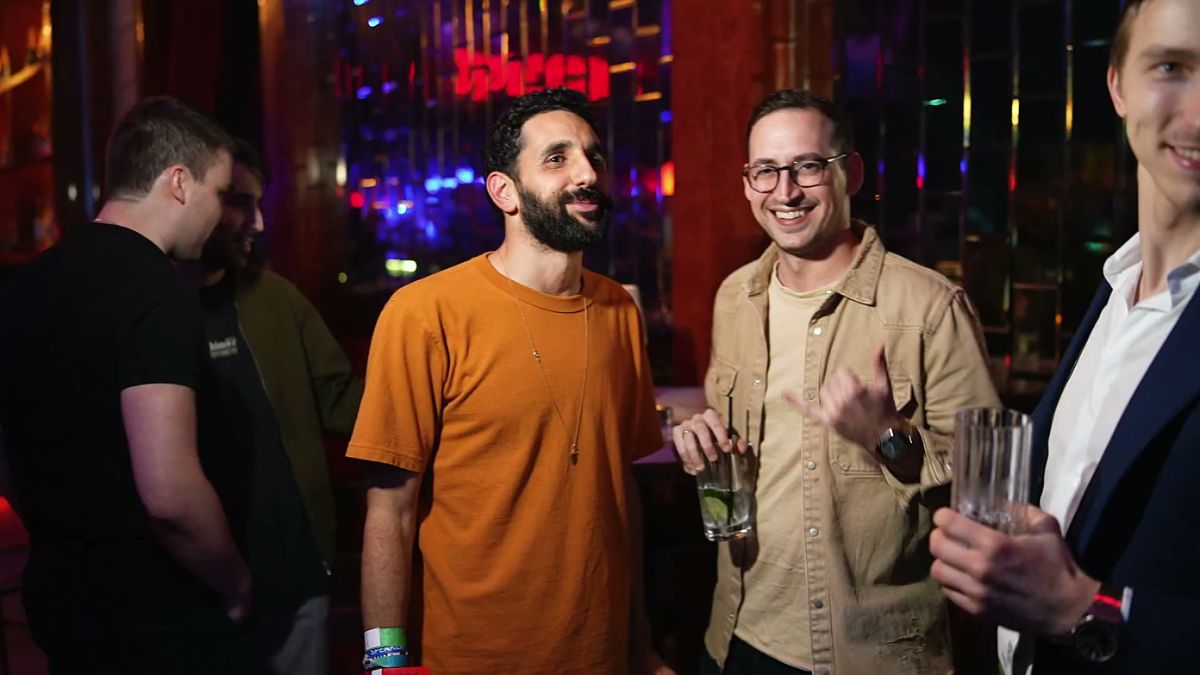 Guests laughing with drinks at the bar during the closing party