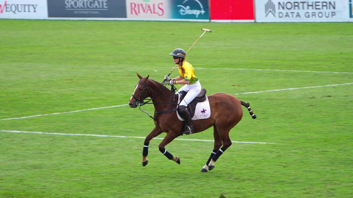Team Cape Town rider galloping with mallet raised in front of pitchside sponsor boards