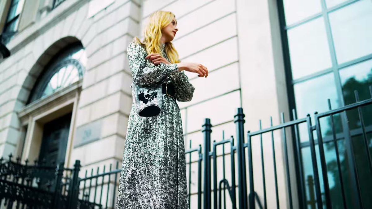 Low-angle shot of the model in a sequin dress against a stone building