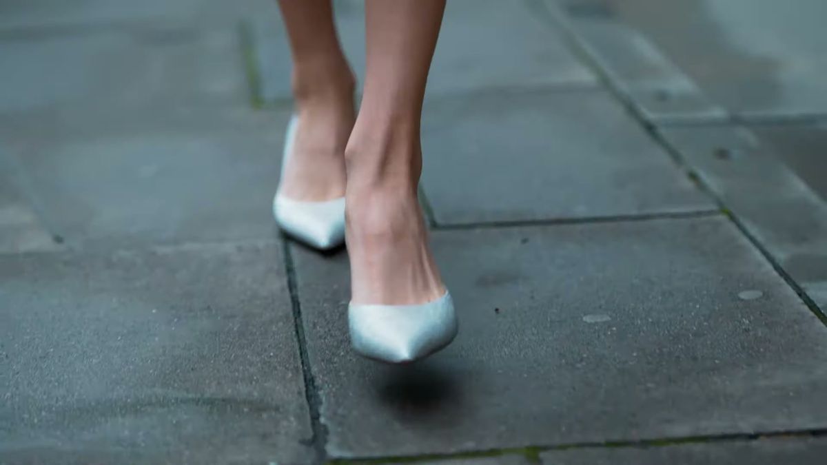 White pointed pumps walking towards a low camera on London paving