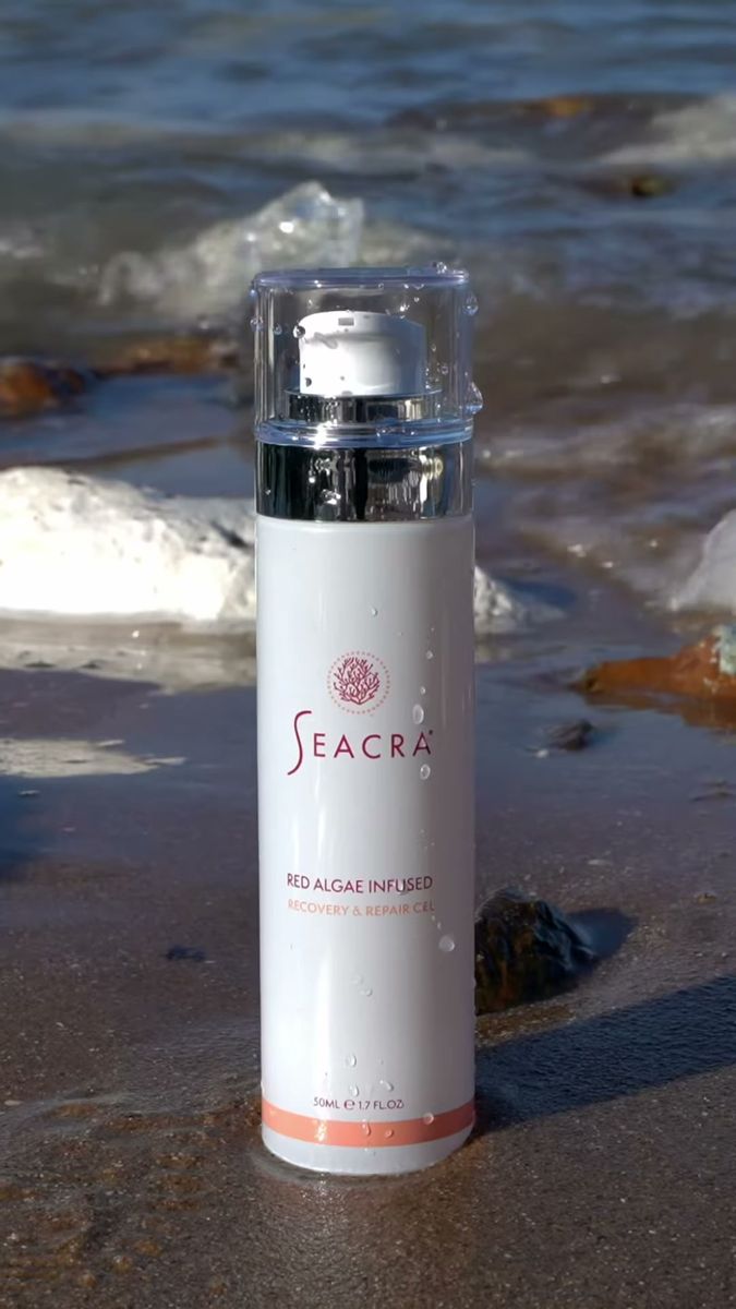 Seacra skincare bottle standing on a beach by the sea