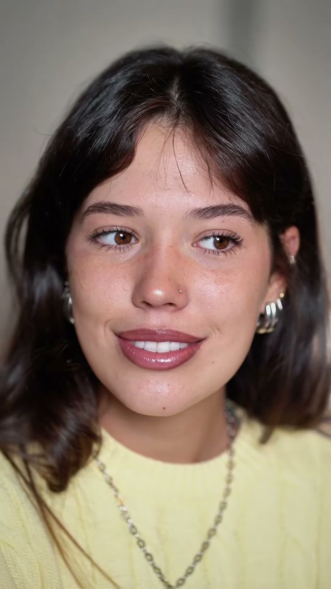 Creator-style skincare video frame of a woman in a yellow jumper smiling at home