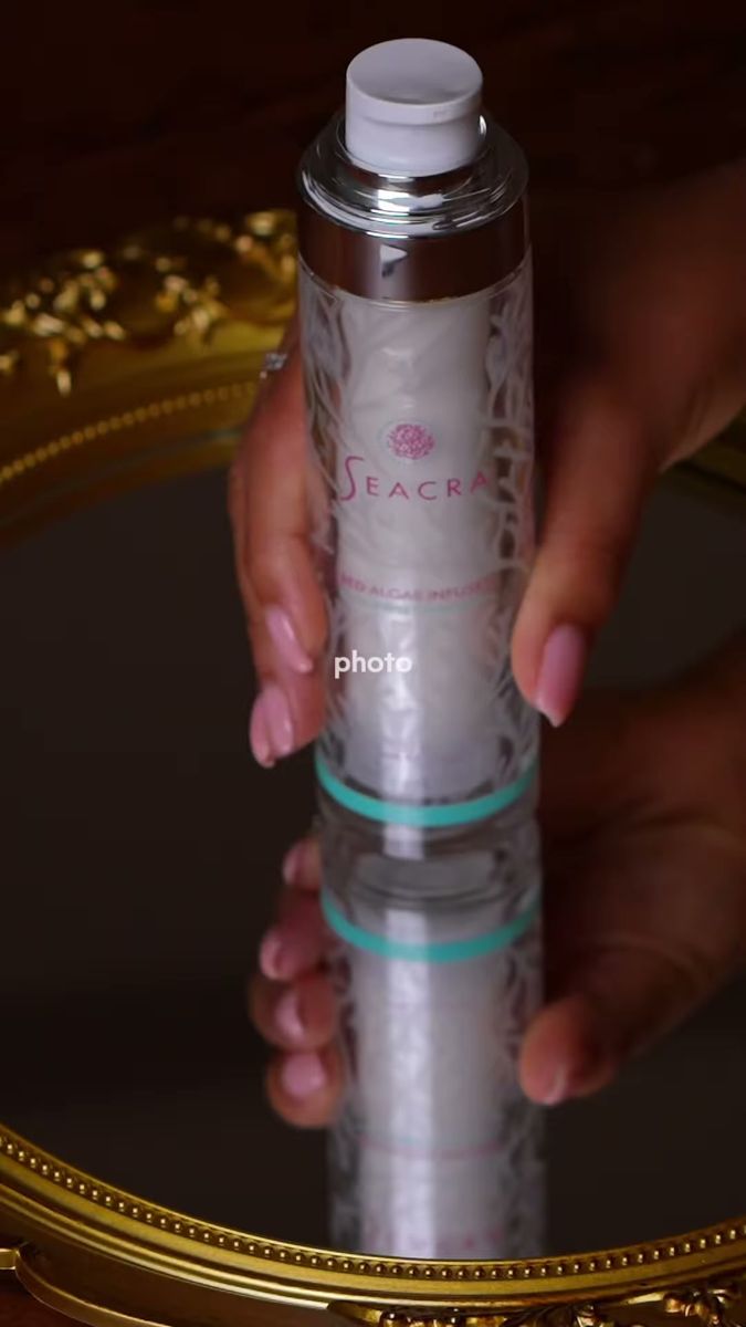 Vertical shot of a skincare bottle held in hand above a mirror