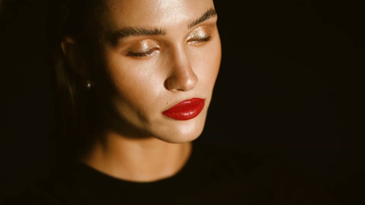 Low-key beauty portrait with a red lip against a dark background