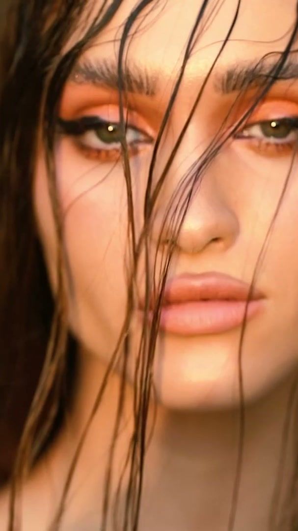 Close-up of wet hair and orange eye make-up in warm light