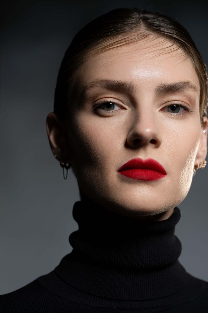 Close-up beauty portrait, matte red lip on a grey backdrop